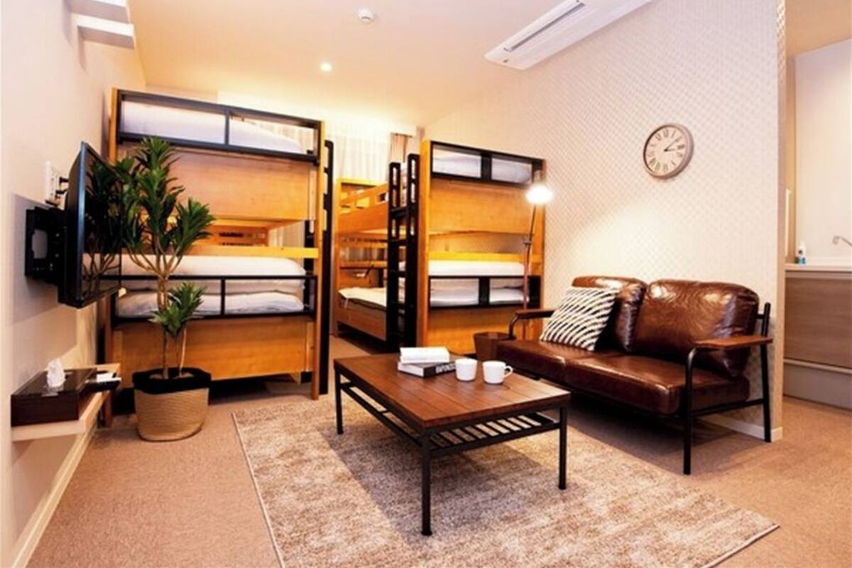 A compact room with bunk beds, a sofa, a coffee table, a TV, and a clock on the wall.