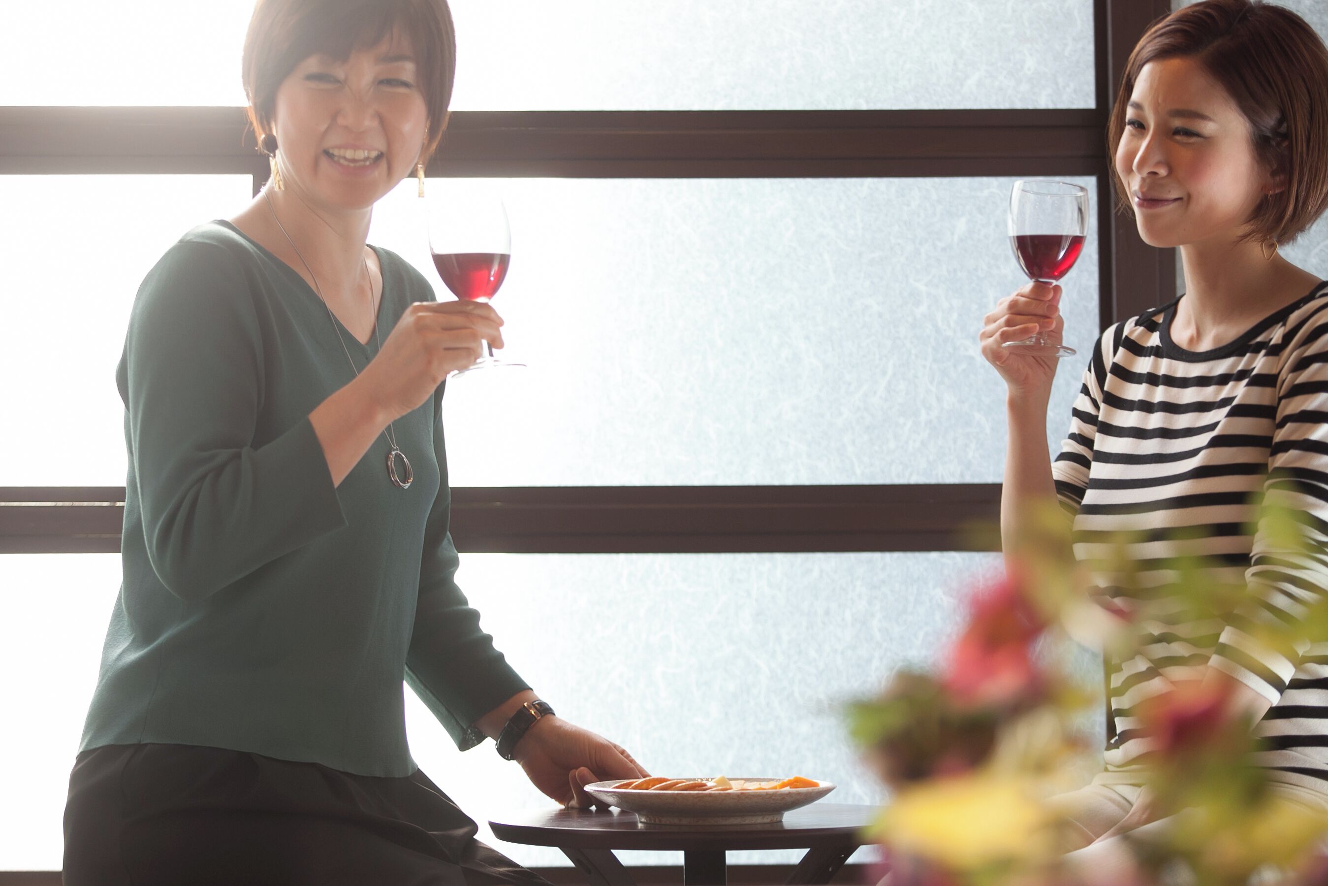 Dos personas sentadas en una mesa con un plato de comida y copas de vino.