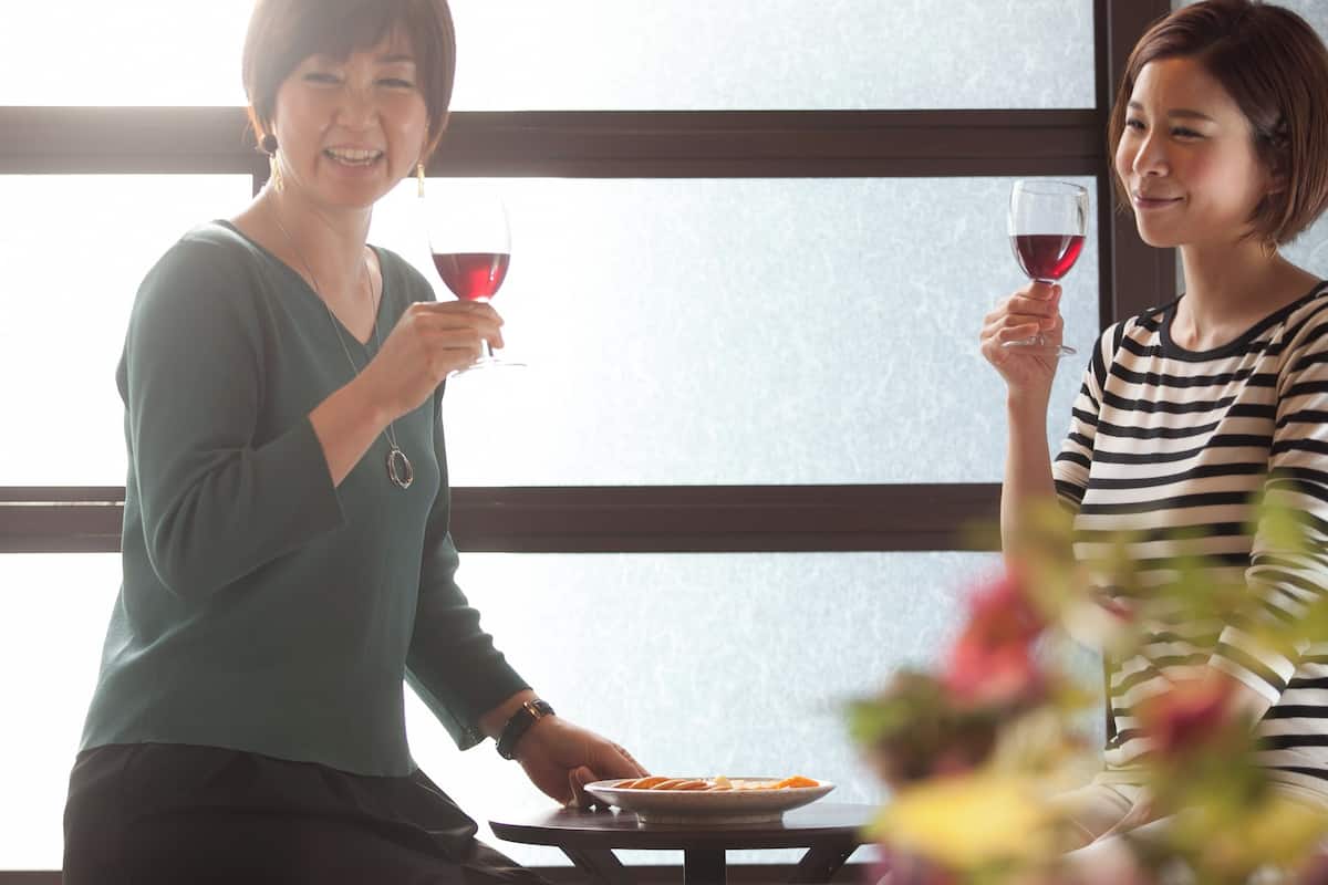 Two people sitting at a table with a plate of food and wine glasses.
