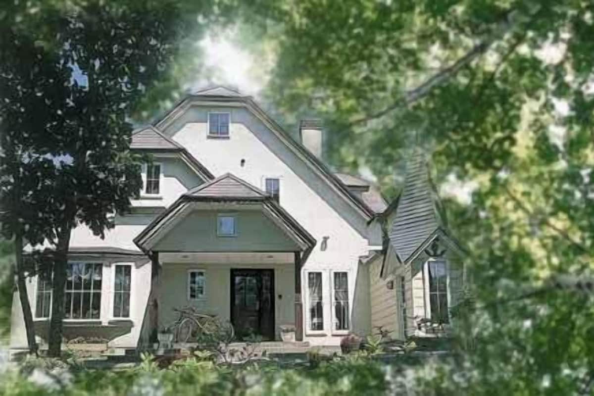 Ein zweistöckiges Haus mit Veranda, Garage und Auffahrt.