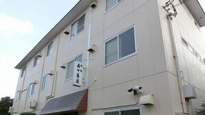 Ein mehrstöckiges Gebäude mit einer flachen Fassade, zahlreichen Fenstern und einem gut sichtbaren Eingang.
