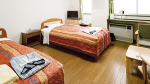 Habitación de hotel con dos camas, un escritorio, una silla, un televisor y una ventana con cortinas.