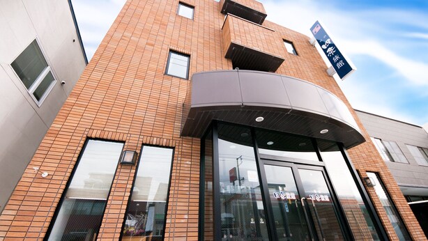 Un edificio moderno con una entrada curva, ventanas amplias y un letrero que indica un restaurante.