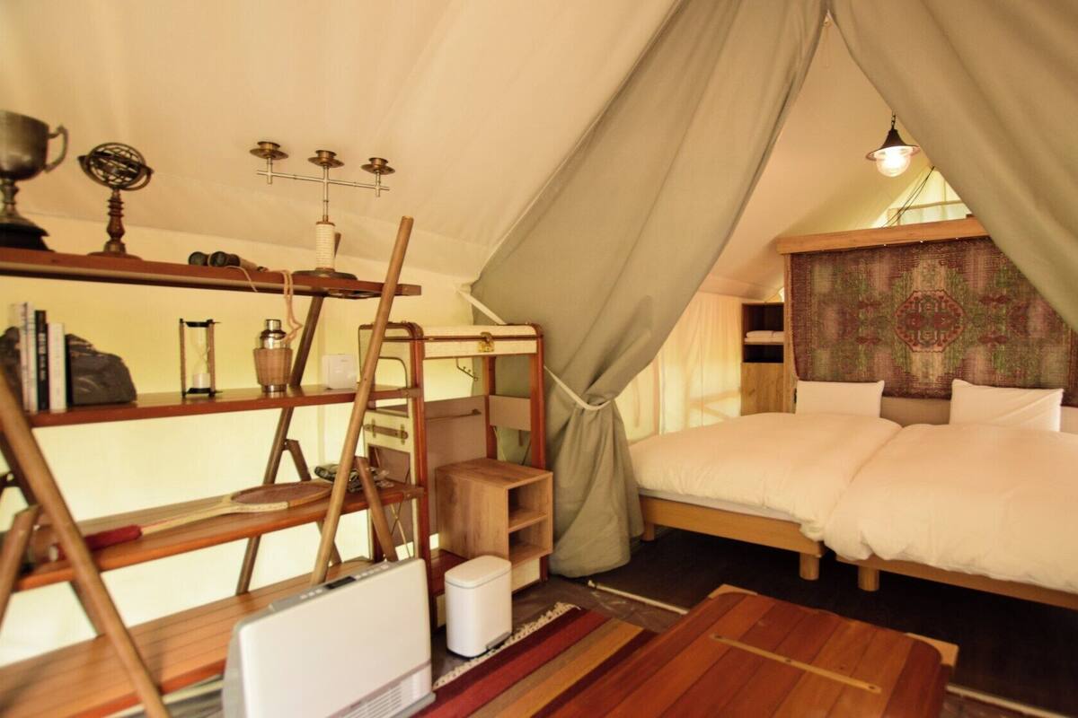 A cozy tent-style bedroom with a bed, shelves, and a small table.