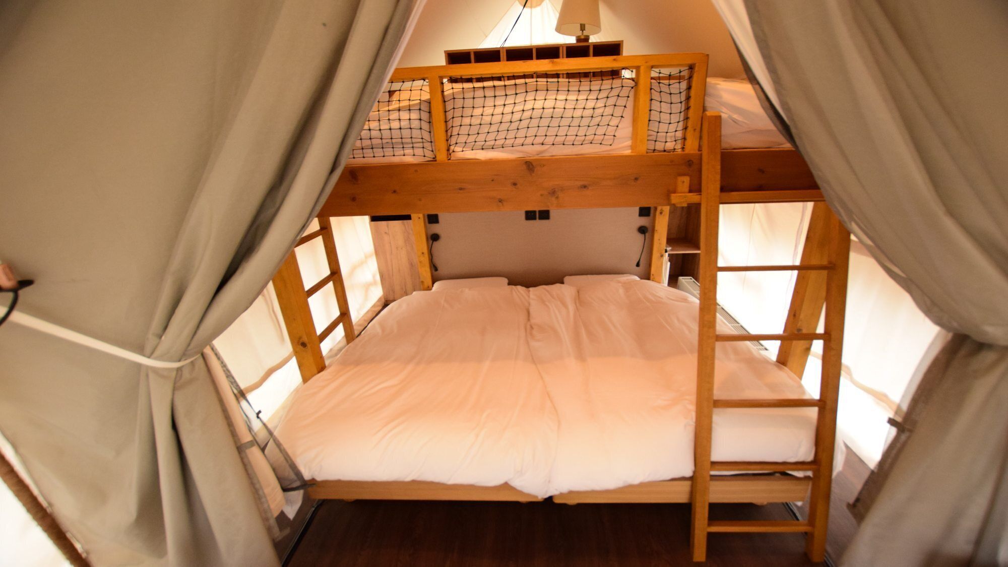 Uma cama beliche com escada, janela e cortina.