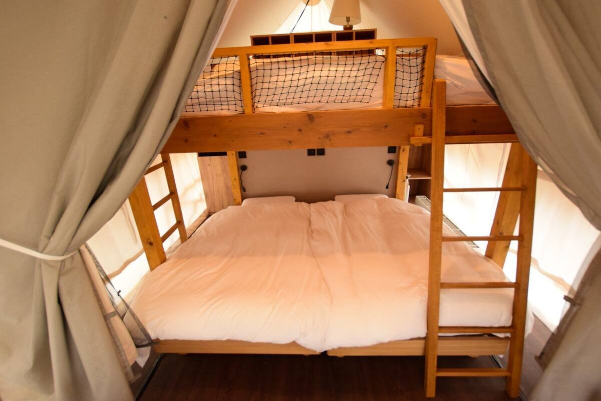 A bunk bed with a ladder, a window, and a curtain.
