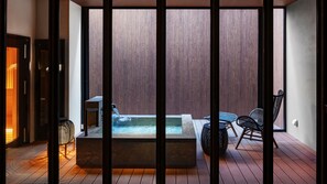 A spa area with a hot tub, seating, and a wooden wall.