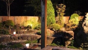 Puinen pergola, jossa on poreallas ja maisemoitu puutarha-alue.