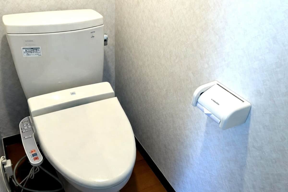 Des toilettes dotées d’un panneau de commande, d’un bidet fixé au mur et d’une unité de contrôle placée au sol.