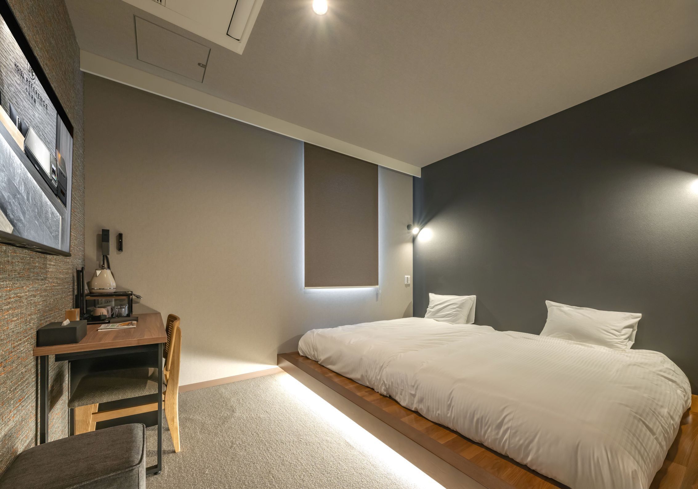 Un dormitorio con cama, escritorio, silla y ventana pequeña.