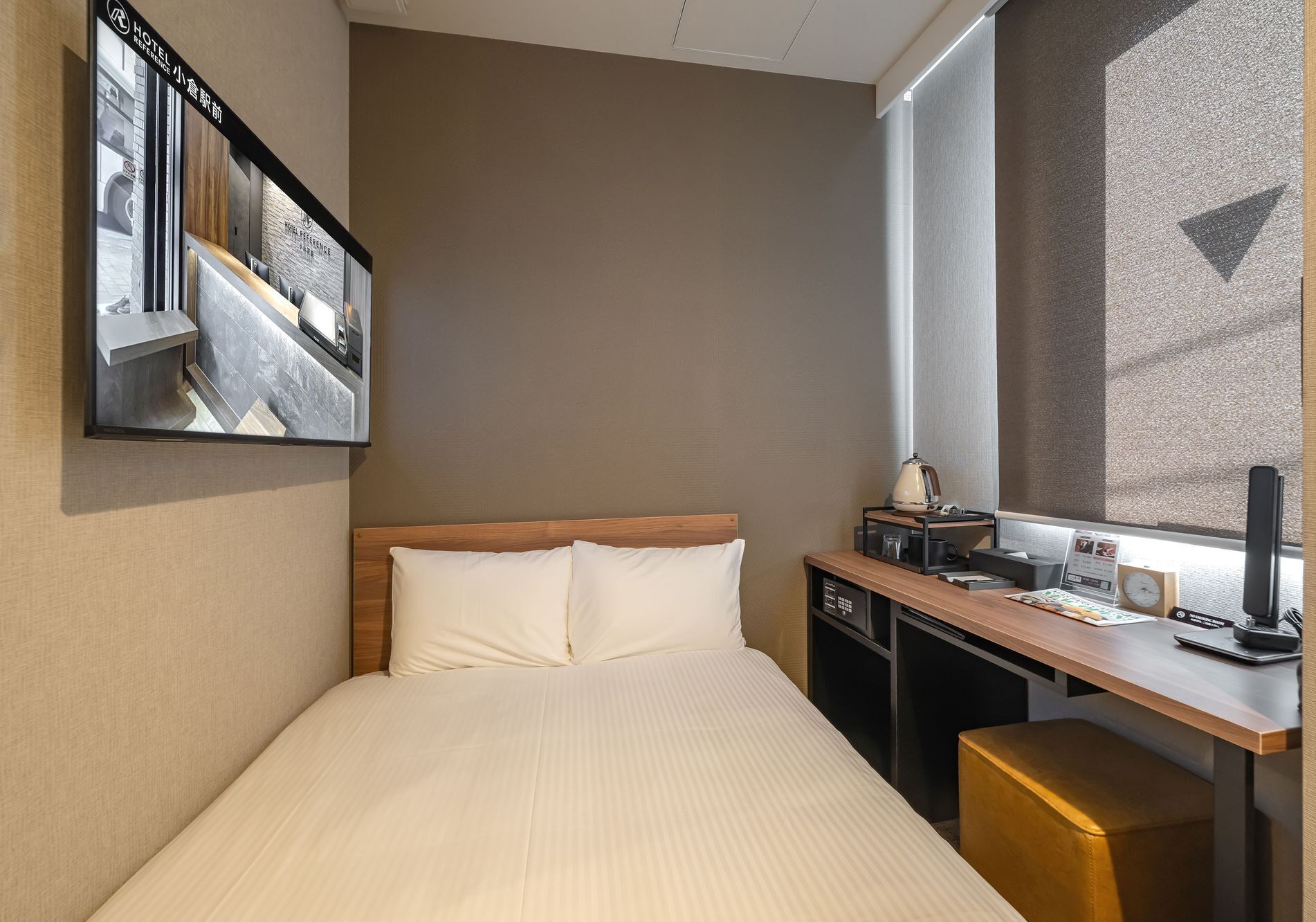 Habitación de hotel con cama, escritorio, lámpara y ventana con vistas.
