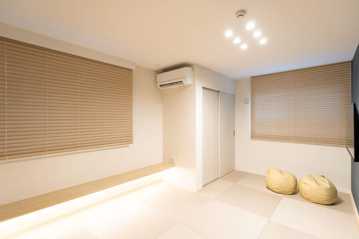 A room with a large window, an air conditioning unit, a door, and two bean bags.