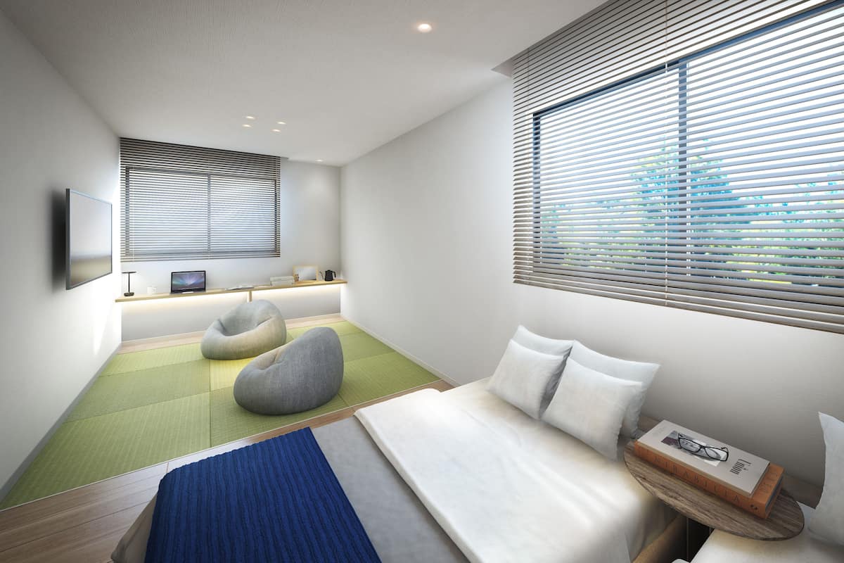 A modern bedroom with a bed, two bean bags, a desk with a computer, and a window with blinds.