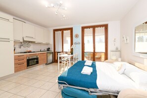 A bedroom with a bed, a bedside table, a window, and a view of the outside. - MGH - Lugana Lake Apartment (Sirmione)