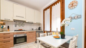 Une cuisine moderne avec des meubles blancs, une table à manger avec des chaises et une plante en pot.