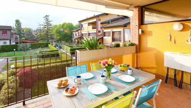 Un balcon avec une table dressée pour le repas, des chaises et une vue sur les bâtiments voisins.