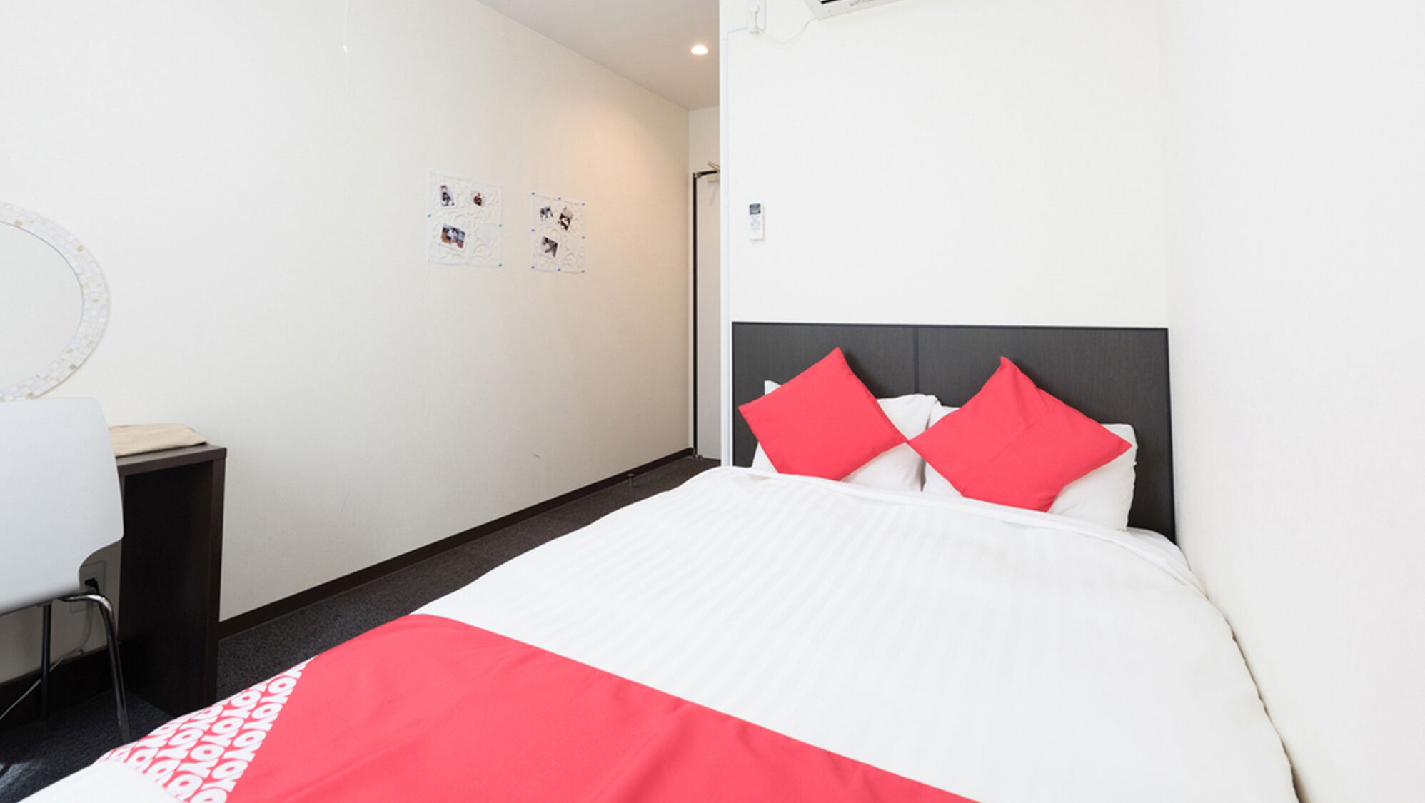 Una habitación de hotel con una cama, una mesita de noche, un espejo y una pared con fotografías.