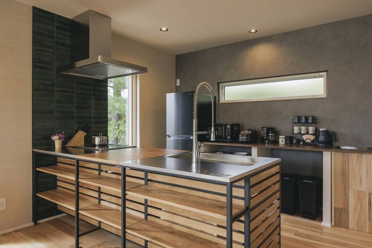 A modern kitchen with a central island, built-in appliances, and a large window.
