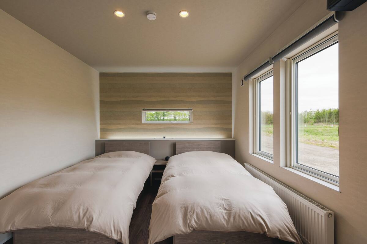 A bedroom with two beds, a window, and a radiator.