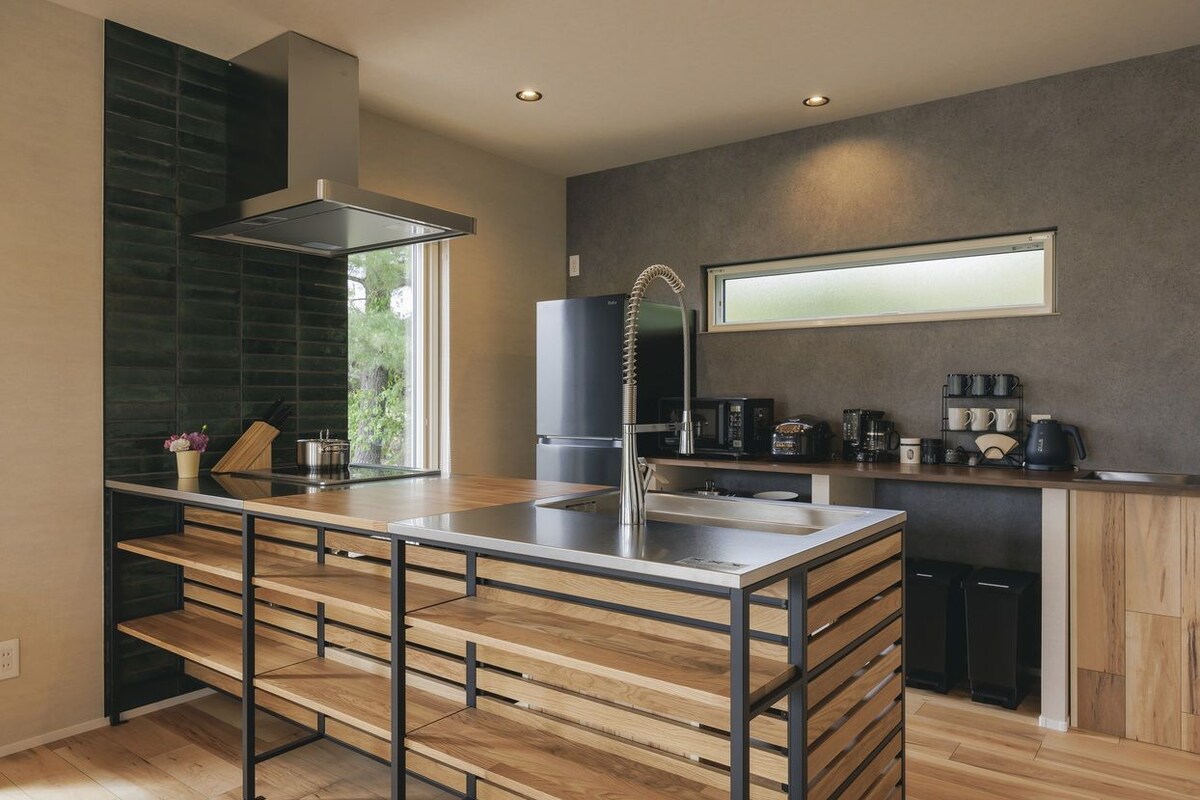 A modern kitchen with a central island, built-in appliances, and a large window.