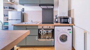 A compact kitchen with a washing machine, microwave, and a built-in oven.