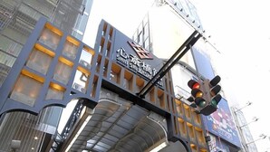 A modern building with a prominent sign, large windows, and a pedestrian overpass. - Business Hotel Urbanty Nishikujo (Osaka)