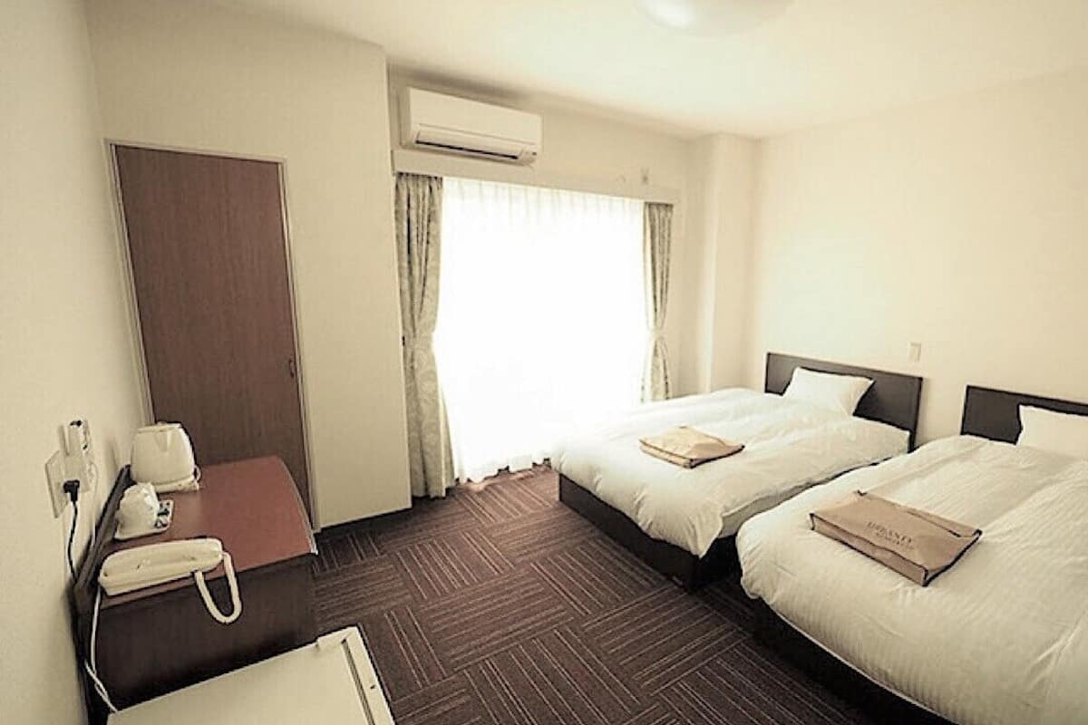 Une chambre d’hôtel avec deux lits, un bureau avec un téléphone et un appareil de climatisation.