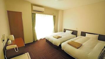 A hotel room with two beds, a desk with a telephone, an air conditioning unit, and a door.
