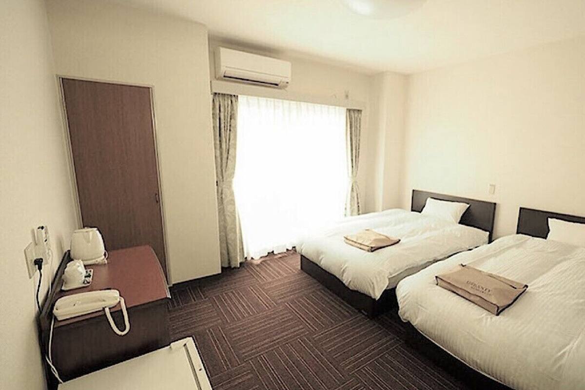 Une chambre d’hôtel avec deux lits, un bureau avec un téléphone et un appareil de climatisation.