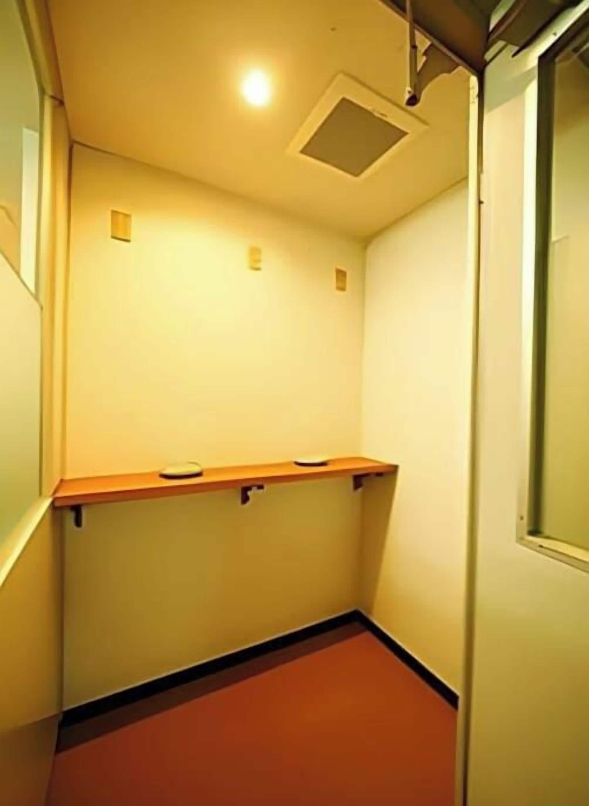 A narrow hallway with a red carpet, a wooden bench, and a door on the right.
