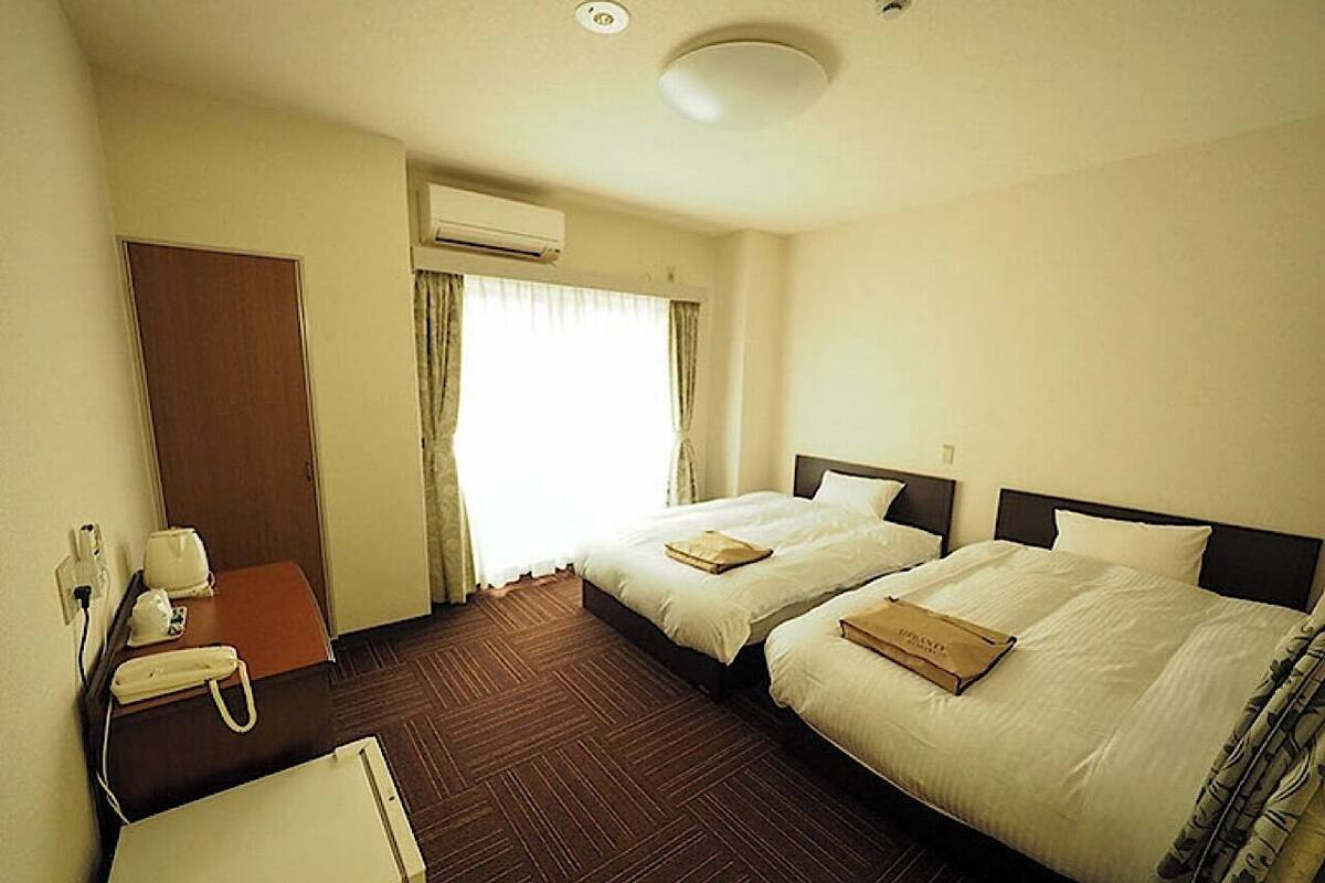 Une chambre d’hôtel avec deux lits, un bureau avec un téléphone et un appareil de climatisation.