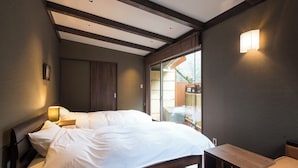 A bedroom with a bed, bedside table, and a view of the outside. - Kitashirakawa Natural Radium Onsen (Kyoto)