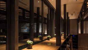 A long wooden table with chairs, large windows, and potted plants. - Kitashirakawa Natural Radium Onsen (Kyoto)