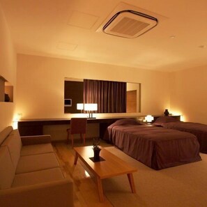 Una habitación de hotel con cama, sofá, escritorio y silla.