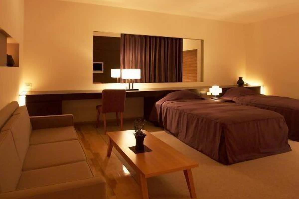 Una habitación de hotel con cama, sofá, escritorio y silla.
