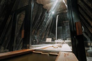 Ein Zimmer mit einer holzverkleideten Schräge, einer Glastrennwand und einem Holztisch mit weißer Tischdecke.