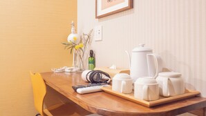 Et lille køkken med et køleskab, kaffemaskine, elkedel og et bord med fjernbetjening og en flaske.