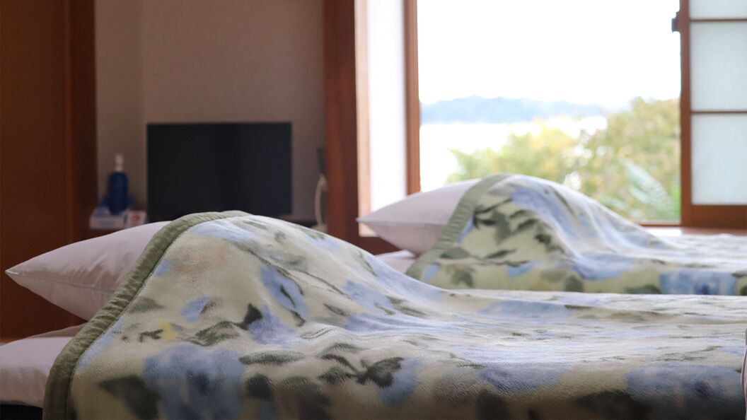 Hotellihuone, jossa on kaksi sänkyä, televisio ja näkymä ulos.