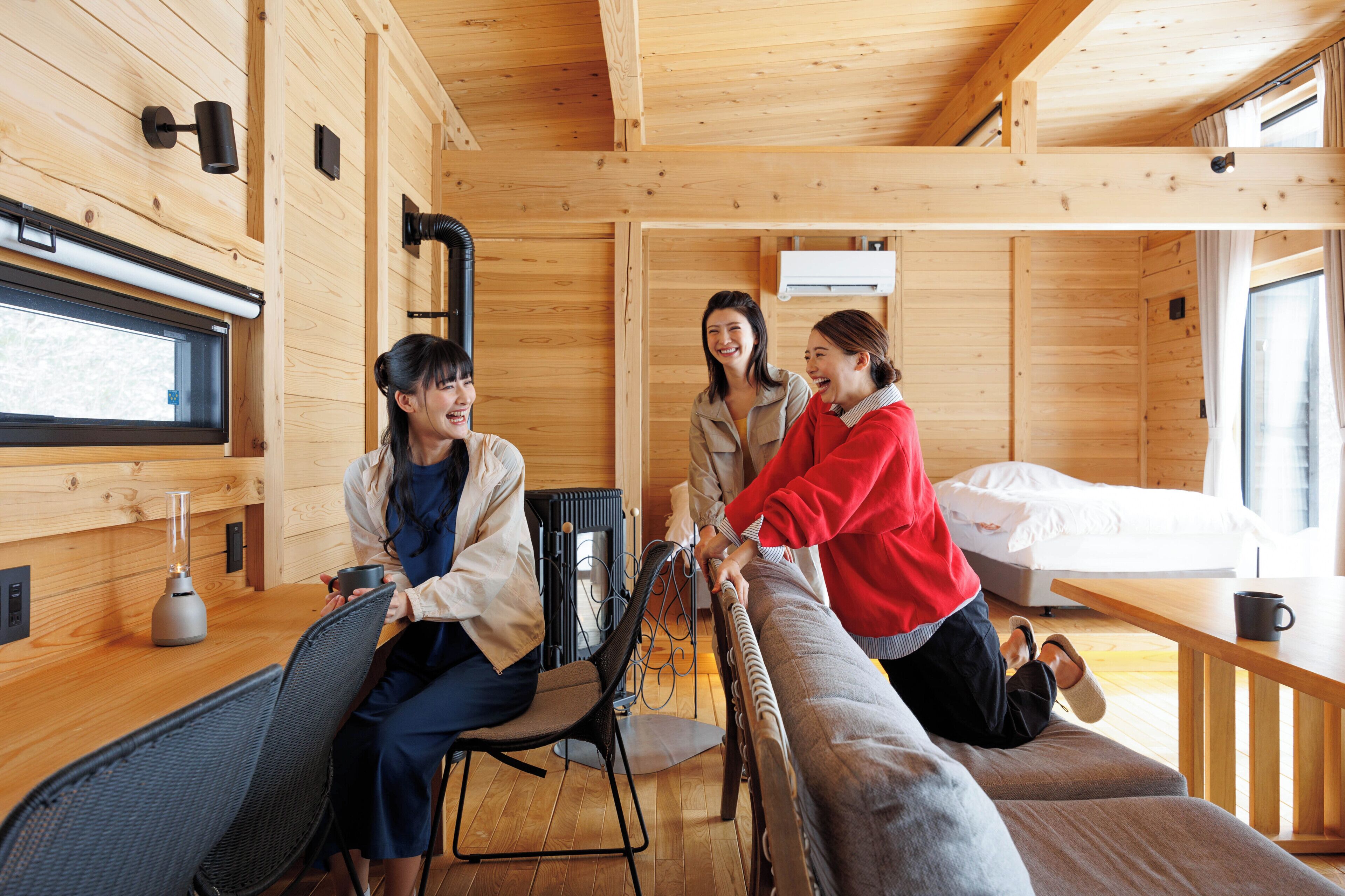 Interior de una cabaña de madera con una cama, una mesa de comedor y una zona de estar.