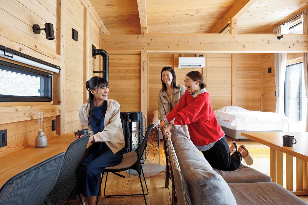 Interior de una cabaña de madera con una cama, una mesa de comedor y una zona de estar.