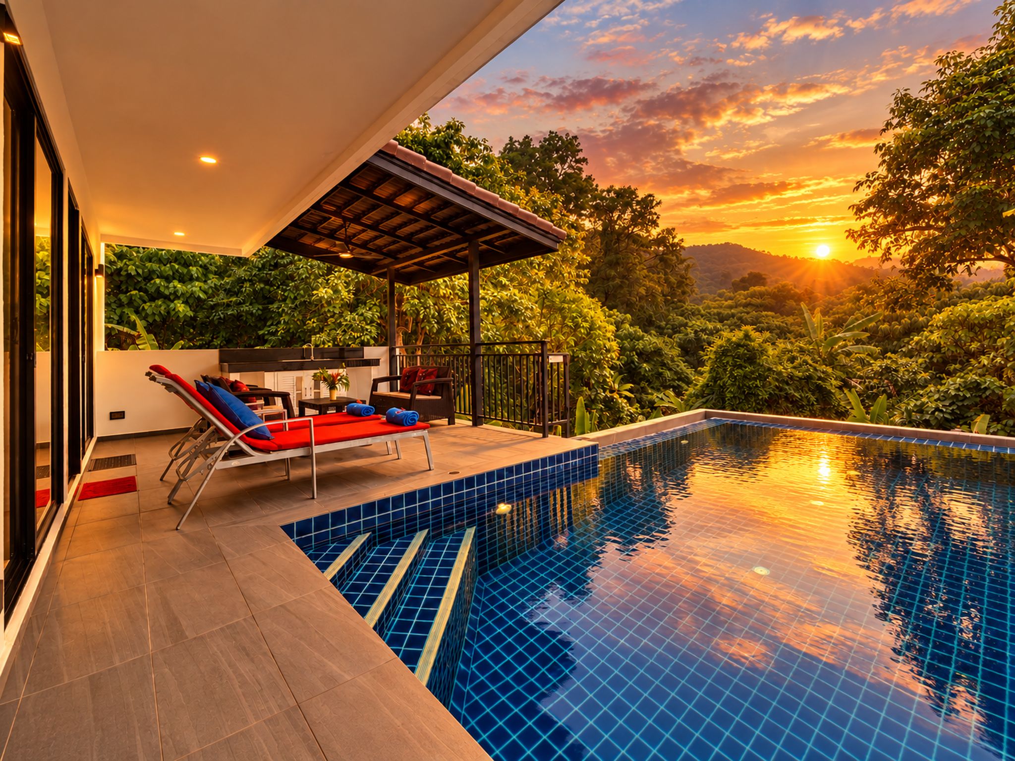 A swimming pool with a tiled edge, a covered seating area with chairs, and a view of the sunset over a forested landscape.