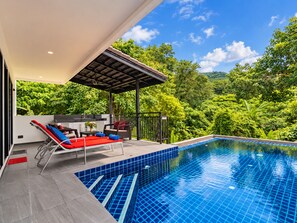 A modern outdoor pool area with a covered seating area and a view of lush greenery. - Luxurious Villa With Private Pool and Stunning Views (Chalong)