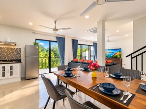 A modern dining area with a wooden table, chairs, and a view of the outdoors. - Luxurious Villa With Private Pool and Stunning Views (Chalong)
