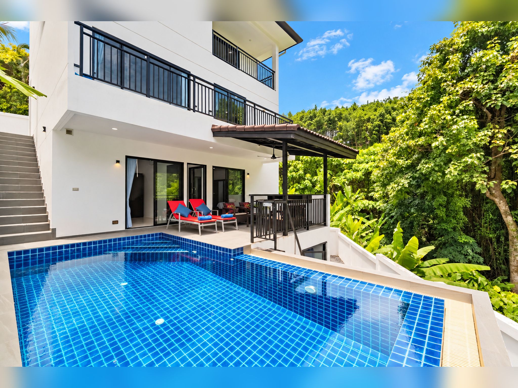 A modern two-story house with a swimming pool, outdoor seating, and lush greenery.