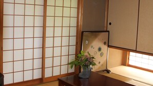 A traditional Japanese room with tatami flooring, sliding shoji doors, a low wooden table, and a plant. - Nishijin Narahian (Kyoto)