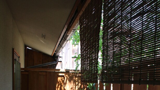 A wooden deck with a round table and a stone planter, enclosed by a bamboo fence. - Nishijin Narahian (Kyoto)