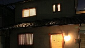 A two-story building with a tiled roof, a front entrance with a door, and two windows on the upper floor. - Nishijin Narahian (Kyoto)
