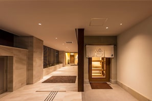 A hotel corridor with a reception desk, a wooden slatted wall, and a tiled floor. - Tabi And Nagasaki (Nagasaki)