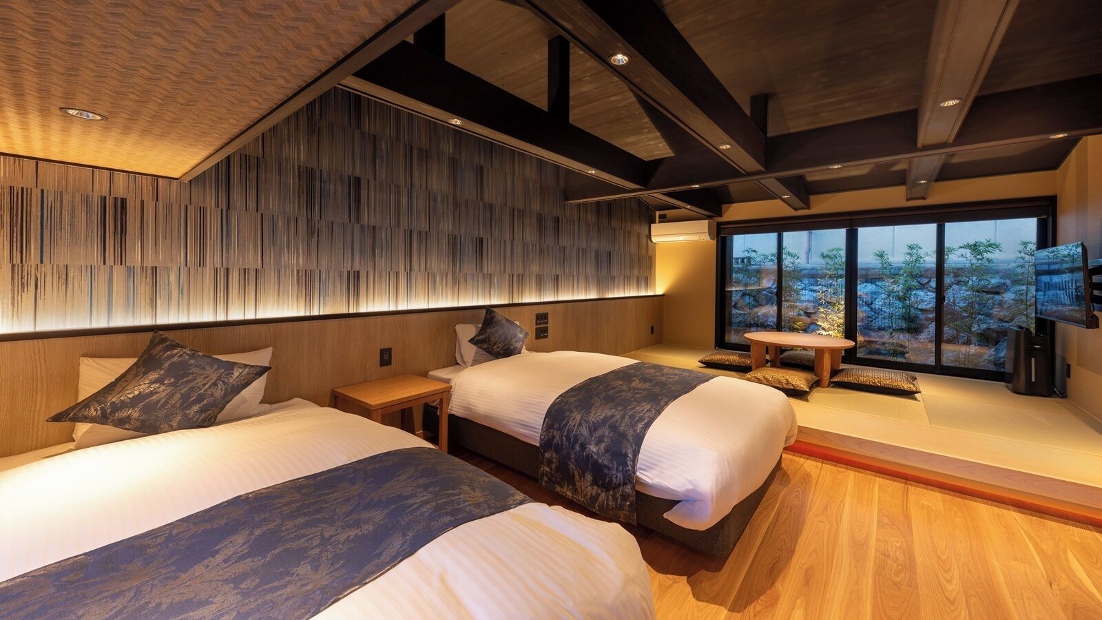 A modern hotel room with two beds, a wooden ceiling, and a large window with a view.