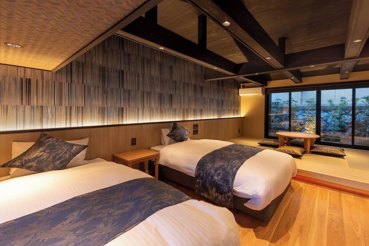 Une chambre d’hôtel moderne avec deux lits, un plafond en bois et une grande fenêtre donnant sur un beau paysage.